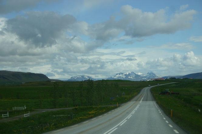 Kilometerlange Straße und schneebdeckte Berge im Hintergrund.